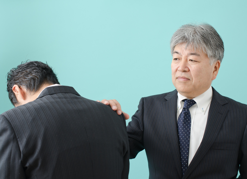 男性が男性の肩に手を置いている画像