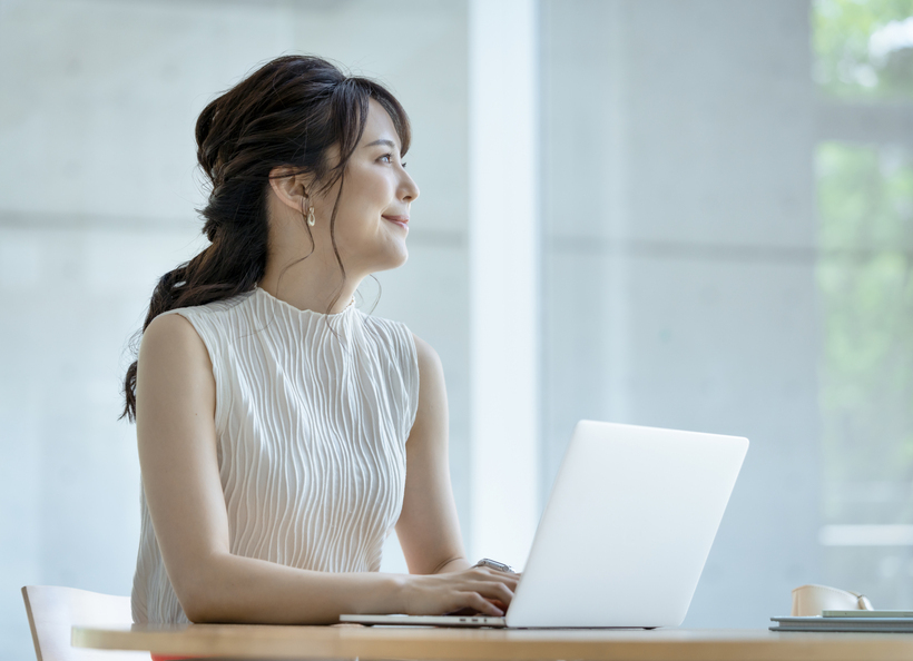 パソコンで何か打つ女性の画像