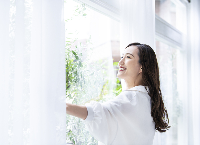 カーテンを開ける女性の画像
