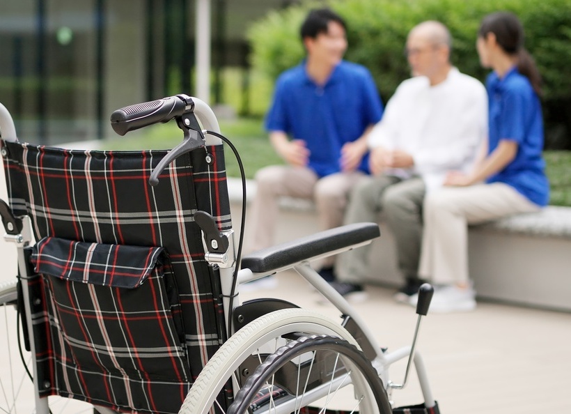 車いすと職員、男性の画像